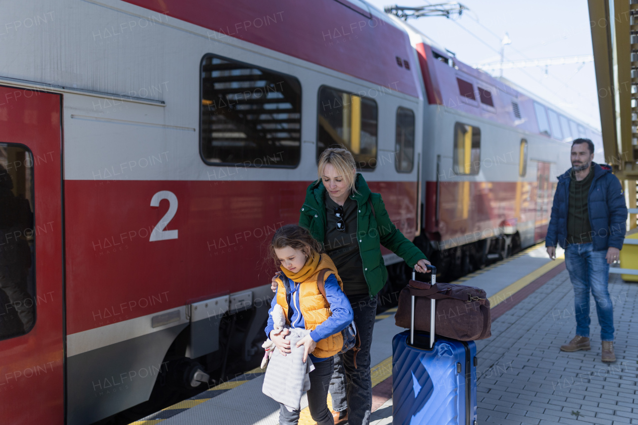 An Ukrainian immigrant family with luggage waiting at train station, Ukrainian war concept.