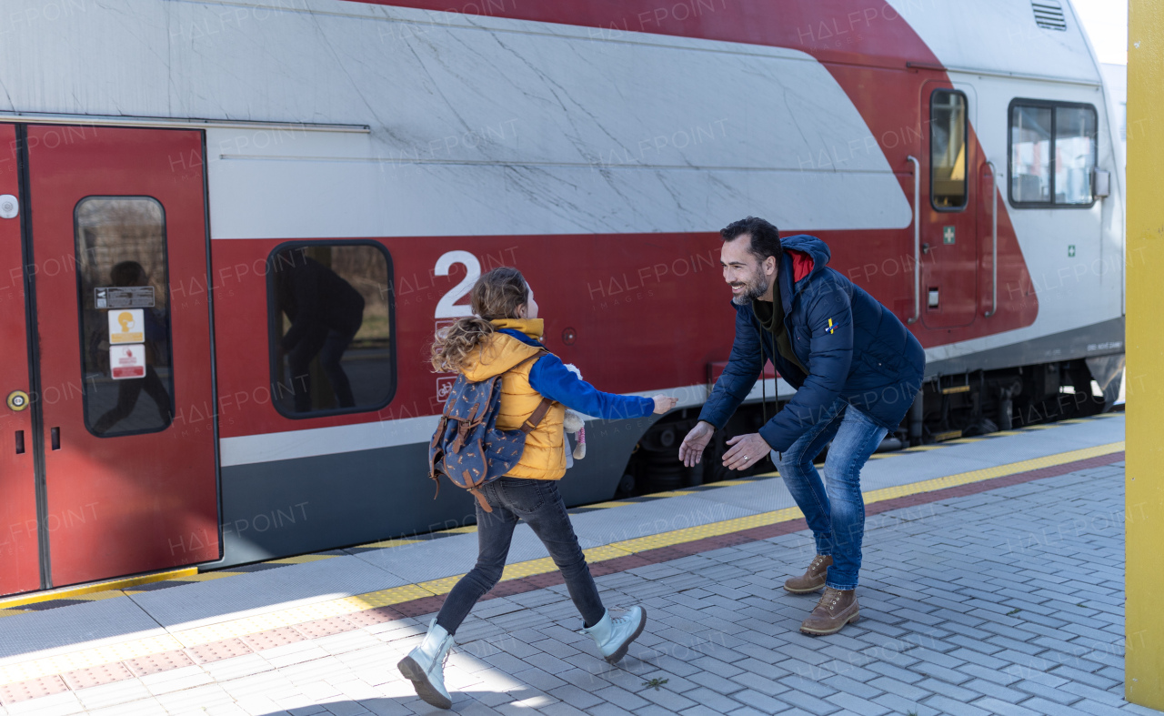 A happy Ukrainian refugee girl running to her father waiting at railway station, reunion after war.