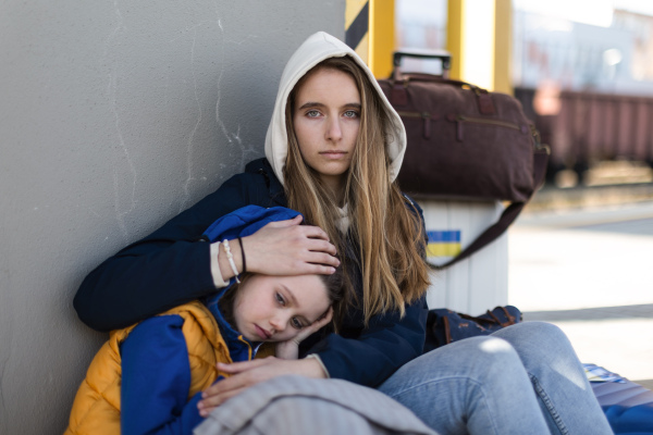 Depressed Ukrainian immigrants sitting and waiting at a railway station.