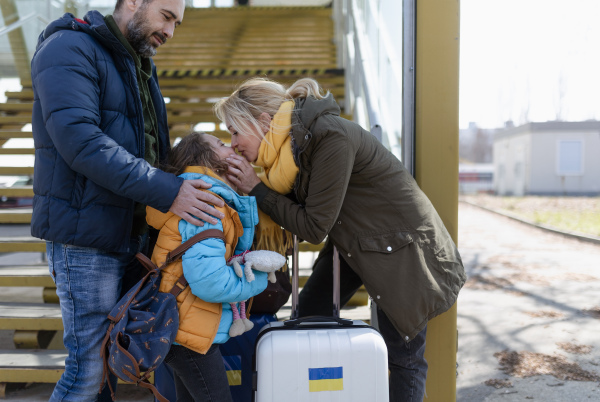 An Ukrainian refugee family with luggage at railway station together, Ukrainian war concept.