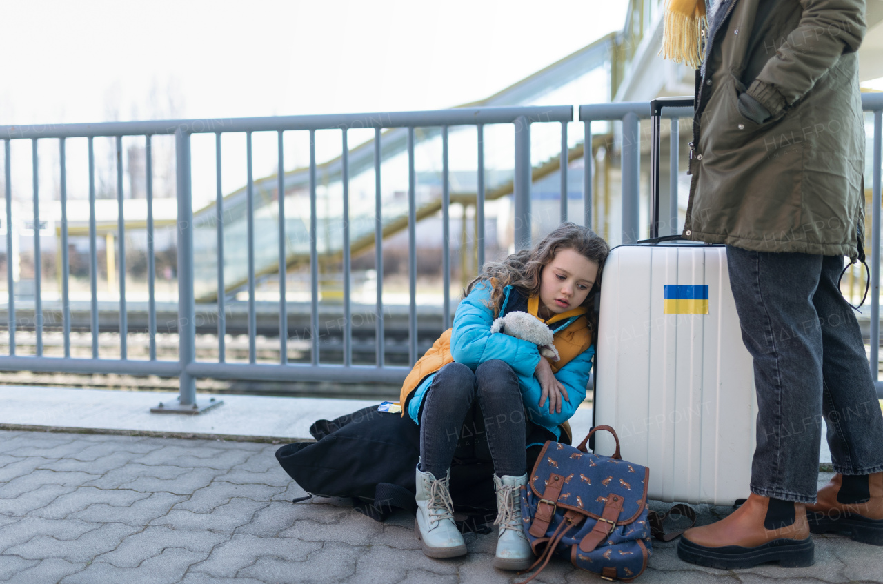 Ukrainian immigrants with luggage waiting at train station, Ukrainian war concept.