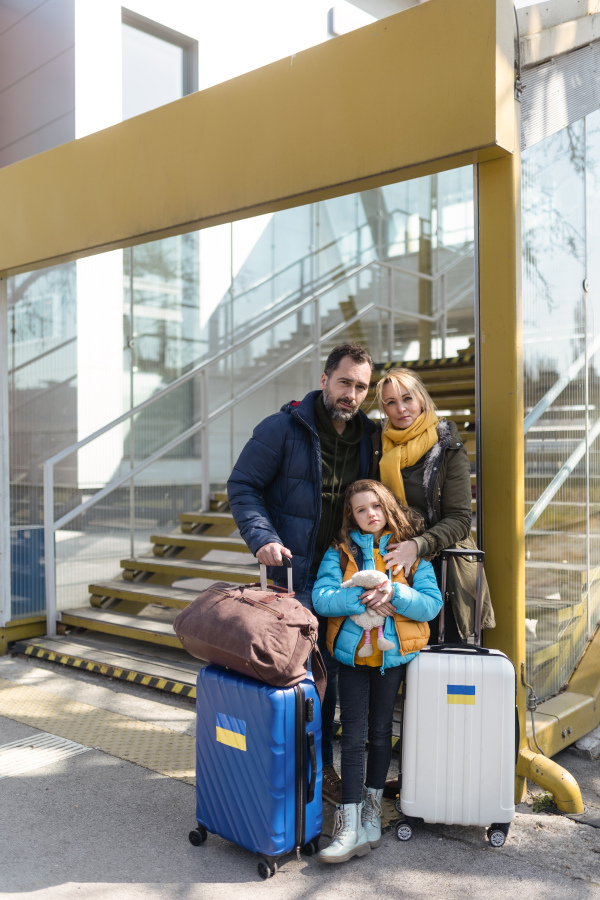 An Ukrainian refugee family with luggage at railway station together, Ukrainian war concept.