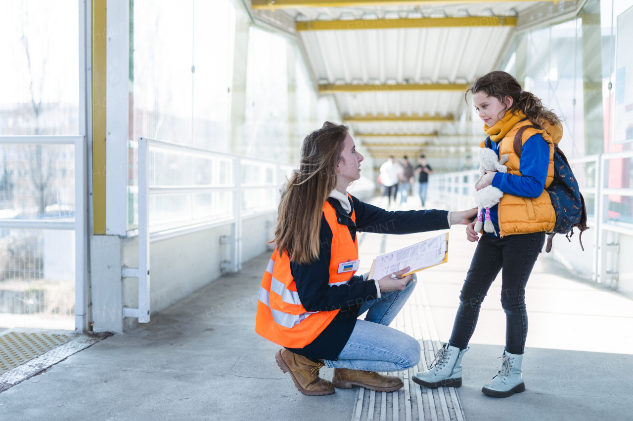 A volunteer helping Ukrainian refugee child at train station.