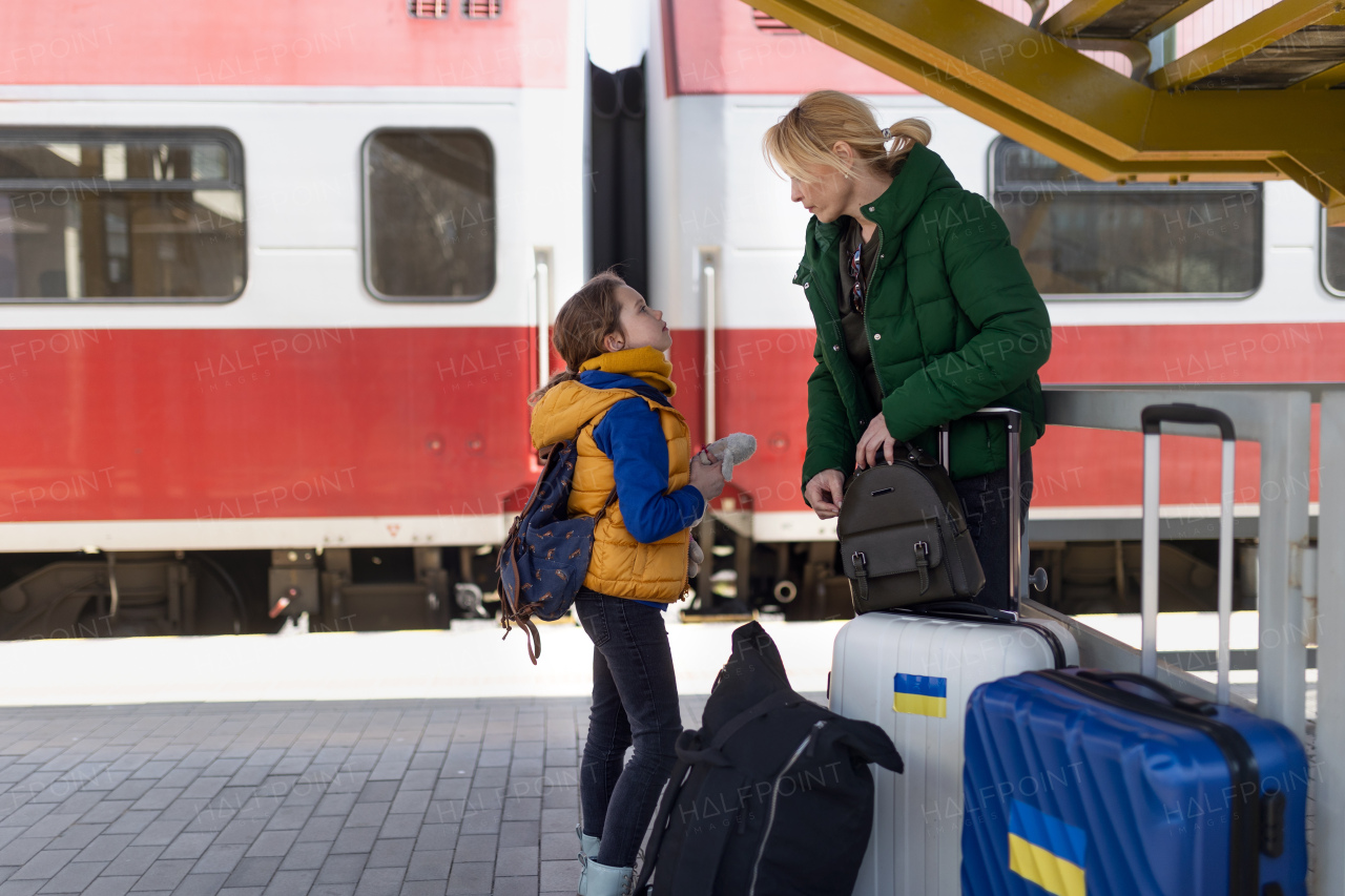 An Ukrainian immigrant family with luggage waiting at train station, Ukrainian war concept.