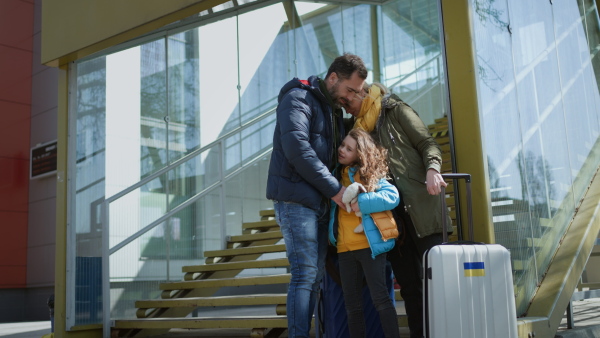 An Ukrainian refugee family with luggage at railway station together, Ukrainian war concept.