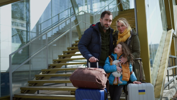 An Ukrainian refugee family with luggage at railway station hugging and saying goodbye, Ukrainian war concept.