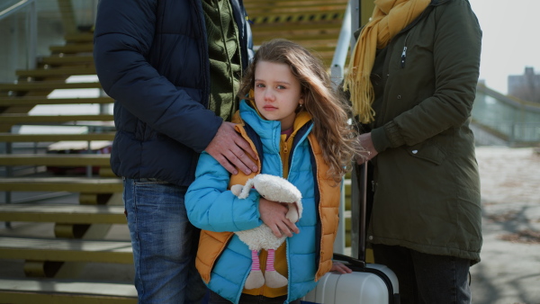 An Ukrainian refugee family with luggage at railway station together, Ukrainian war concept.