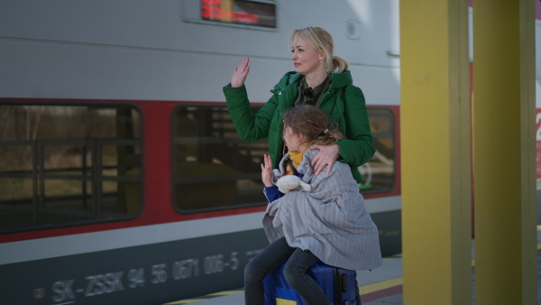 An Ukrainian woman with daughter saying good bye and waving to his family in train leaving Ukraine due to Russian invasion in Ukraine.