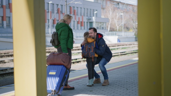 An Ukrainian refugee family hugging at railway station together, reunion after war.