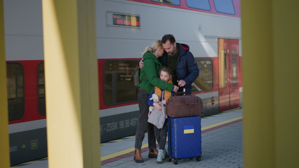 An Ukrainian refugee family with luggage at railway station together, Ukrainian war concept.