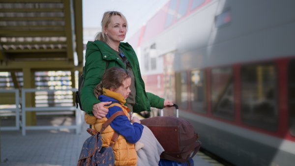 An Ukrainian woman with daughter standing at train station leaving Ukraine due to Russian invasion in Ukraine.