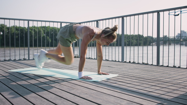 Mid adult woman doing exercise on a mat outdoors in city, healthy lifestyle concept.