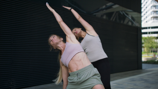 A group of young and old women doing exercise outdoors in city.