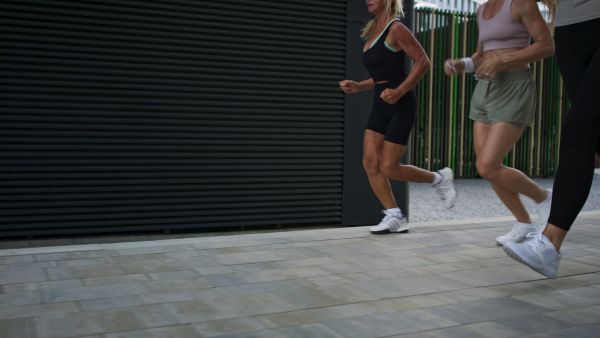 A low section of group of young and old women running outdoors in city, healthy lifestyle concept.