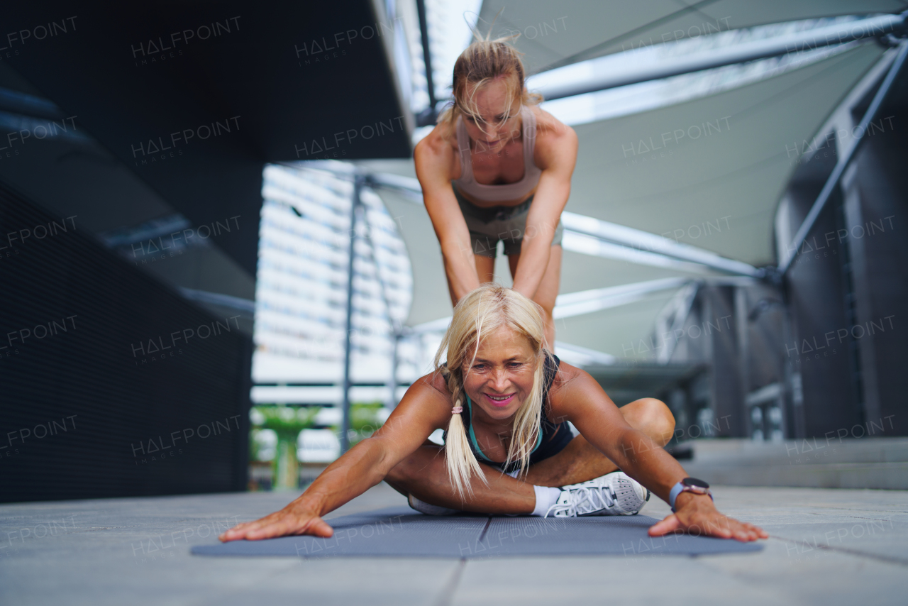 Two happy women doing exercise outdoors in city, healthy lifestyle concept.