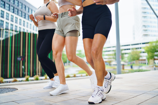 A group of unrecognizable women doing exercise outdoors in city, running.