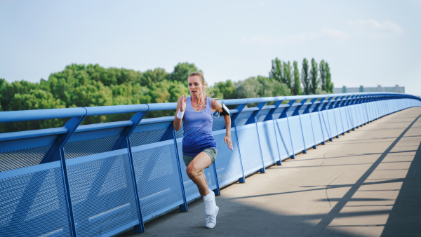 A mid adult woman running outdoors in city, healthy lifestyle concept.