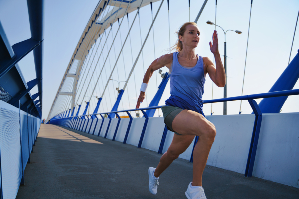 A mid adult woman running outdoors in city, healthy lifestyle concept.