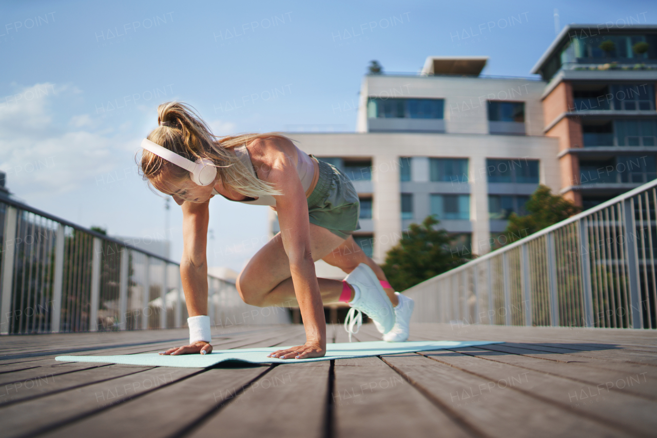 A mid adult woman doing exercise outdoors in city, healthy lifestyle concept.