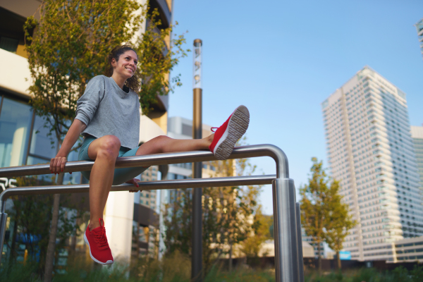 Happy mid adult woman doing exercise on parallel bars outdoors in city, healthy lifestyle concept.