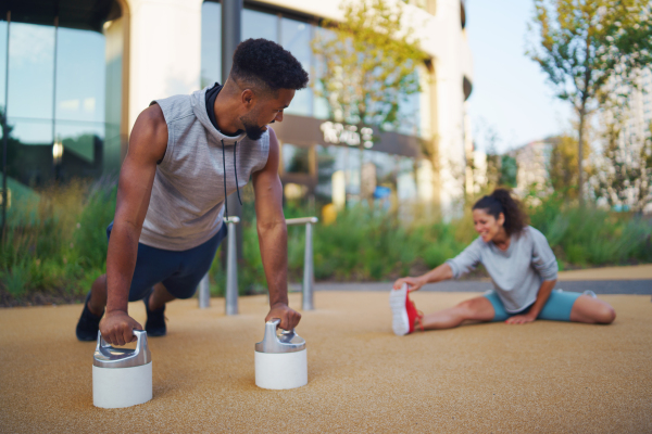 Happy man and woman couple friends doing workout exercise outdoors in city, talking.