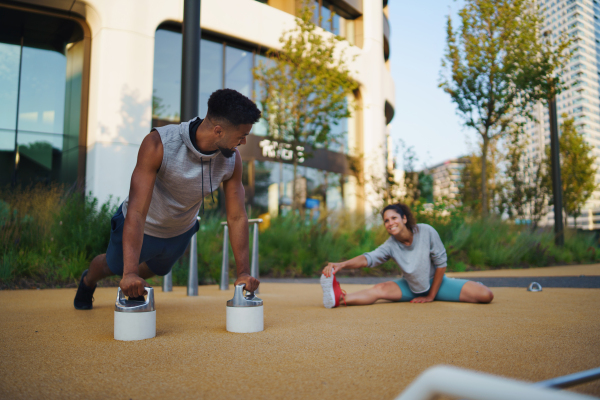 Happy man and woman couple friends doing workout exercise outdoors in city, talking.