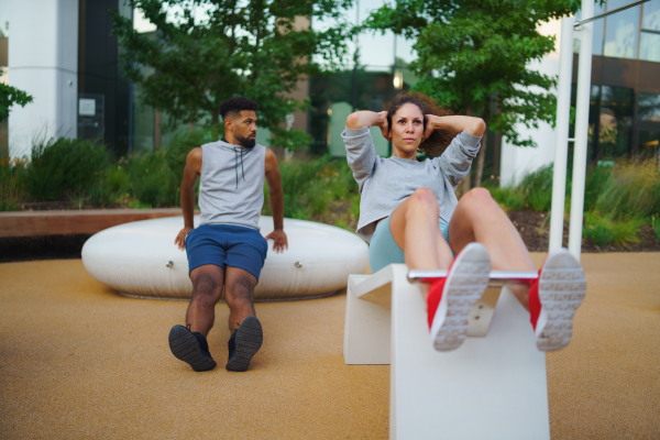 A man and woman couple friends doing exercise outdoors in city workout park