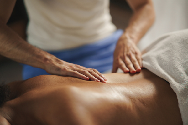 An unrecognizable young woman having relaxing back massage at the spa.