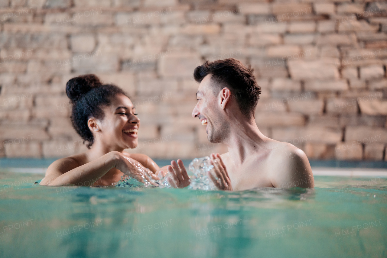 A portrait of happy young couple in love in swimming pool, talking.