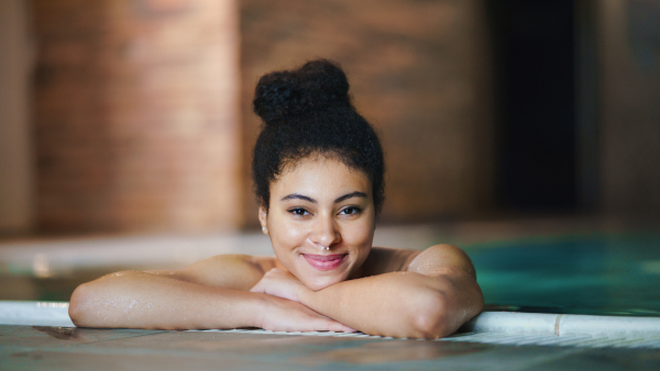 Portrait of happy young woman in indoor swimming pool, looking at camera.