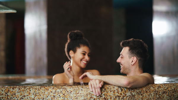 A portrait of happy young couple in love in swimming pool, having fun.