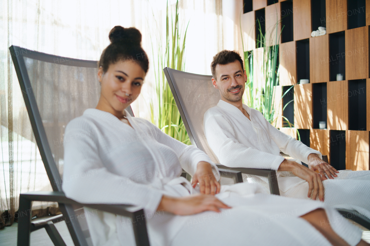 Portrait of happy young couple sitting and looking at camera in spar resort, relaxing.