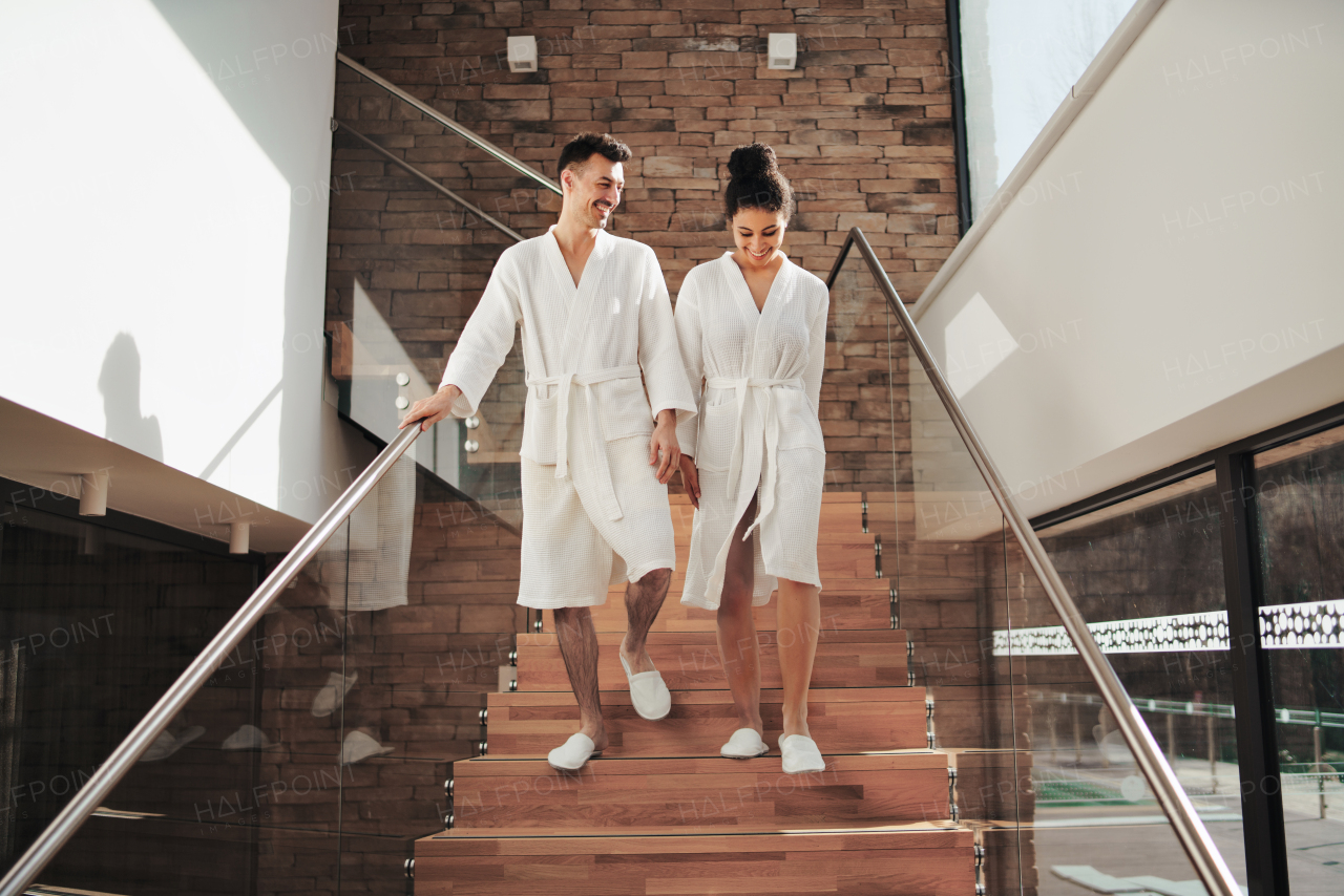 A portrait of young couple in spa resort, walking down the stairs.