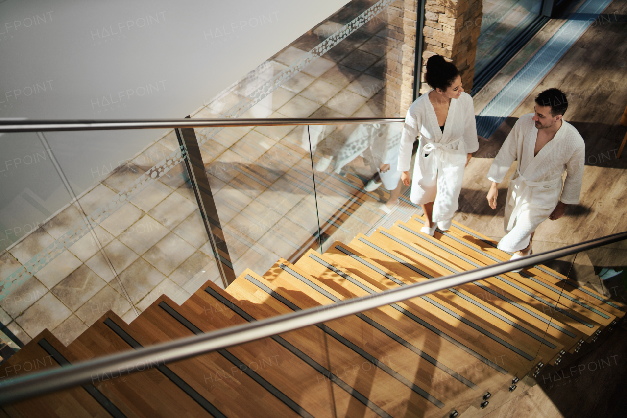 A top view of happy young couple in spa resort, walking up the stairs.