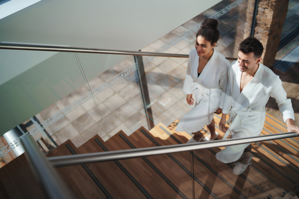 A top view of happy young couple in spa resort, walking up the stairs.