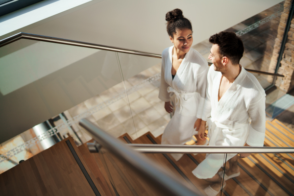 A top view of happy young couple in spa resort, walking up the stairs.