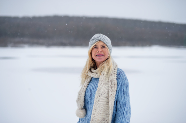 Front view portrait of happy senior woman outdoors standing in snowy nature.