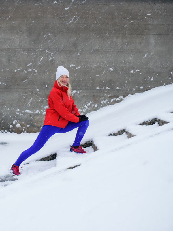 Side view of an active senior woman outdoors in snowy winter, doing exercise.