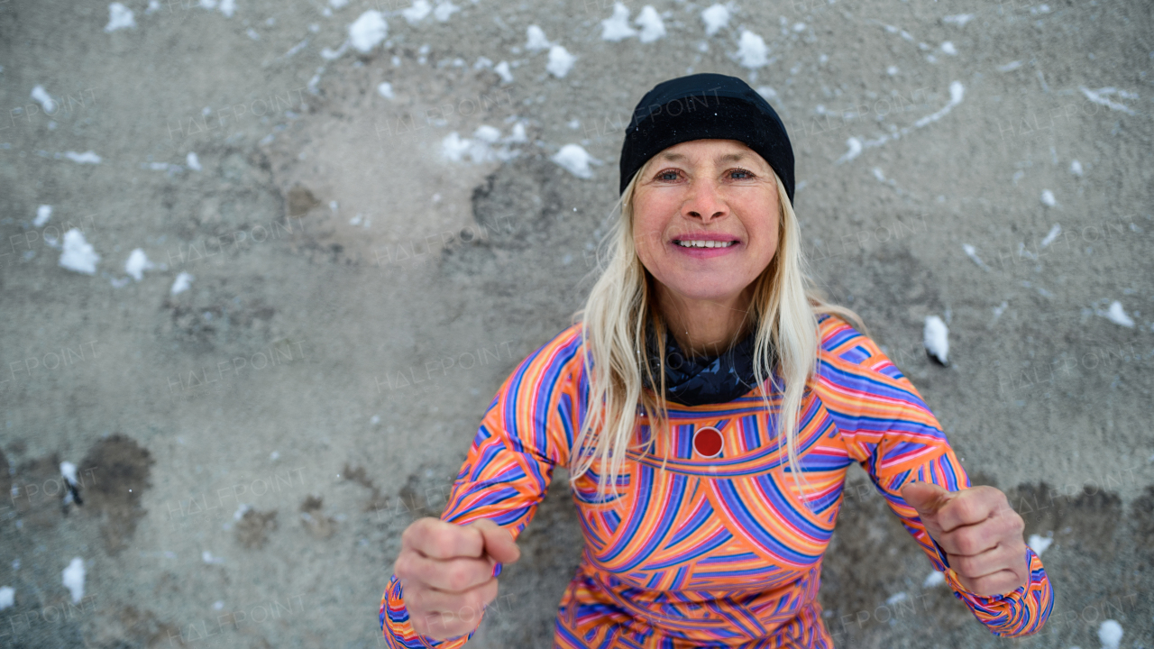 Portrait of active senior woman doing exercise outdoors in winter, getting ready for cold therapy.