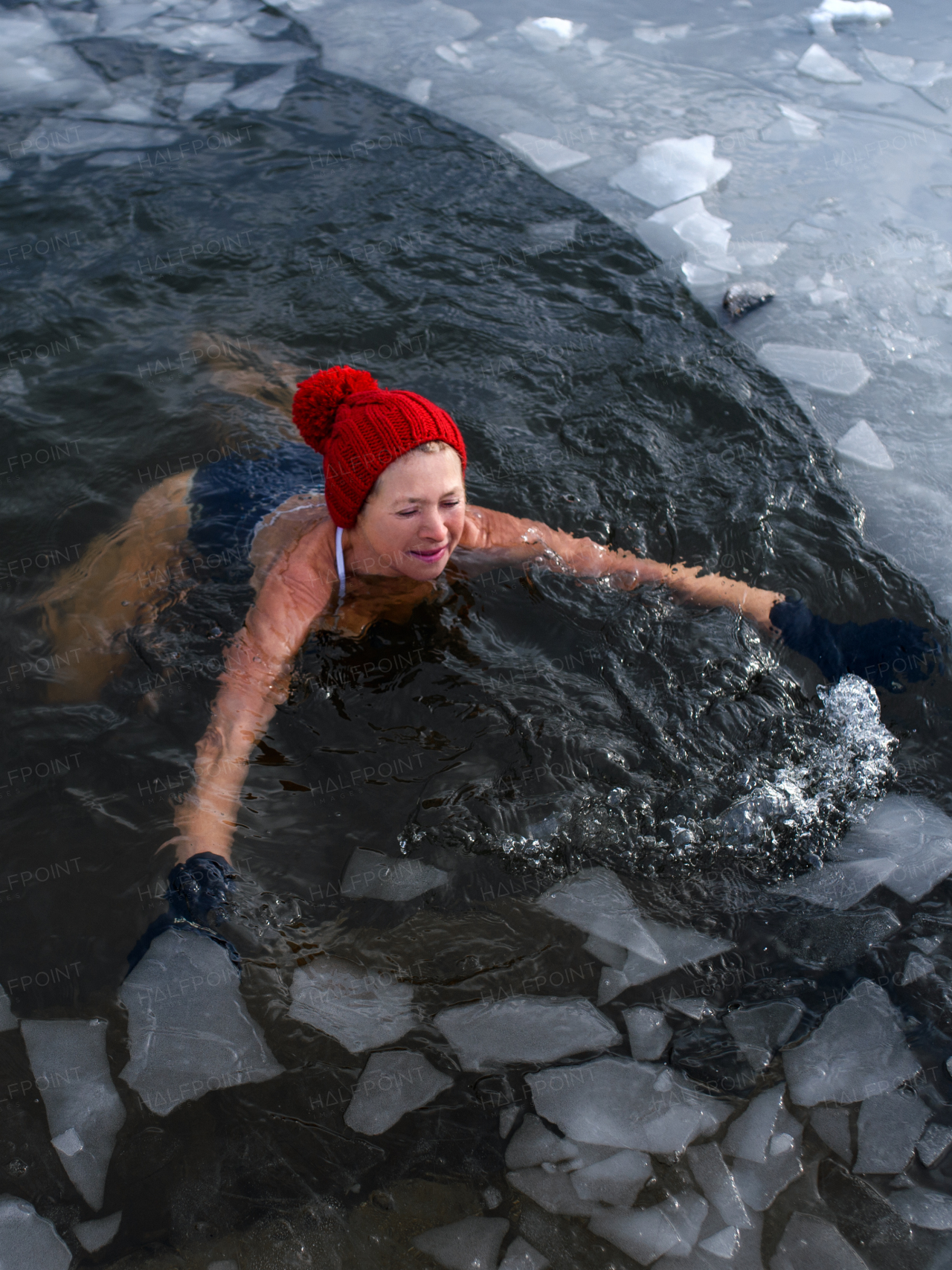 A high-angle view of active senior woman in swimsuit outdoors in winter, cold therapy concept.