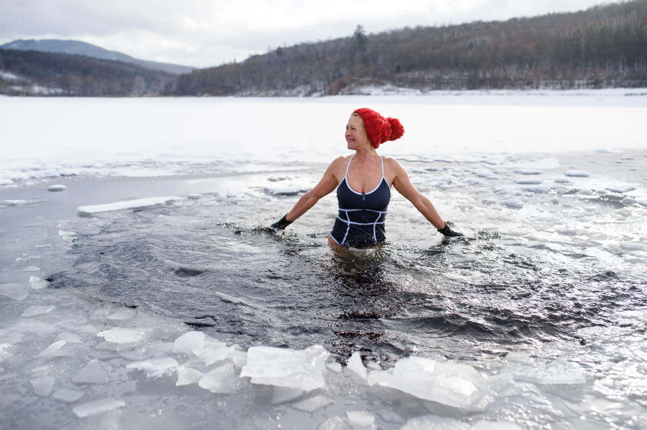 A front view of active senior woman in swimsuit outdoors in winter, cold therapy concept.