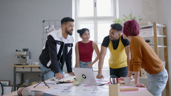 A group of young editors in the office, working together on project and looking at camera.