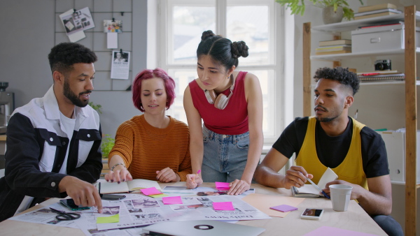 A group of young editors in the office, working together on project and looking at camera.