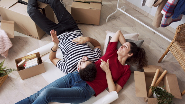 Top view of happy young couple owners in new flat, moving in, talking and planning. New home and relocation concept.