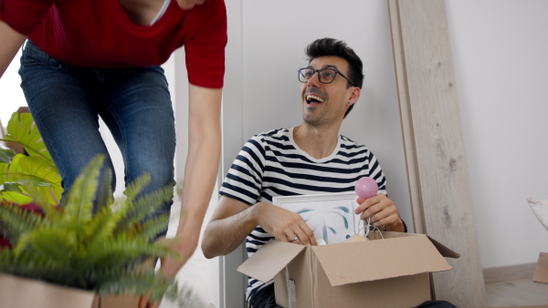 Happy young couple with boxes moving in new flat, new home and relocation concept.