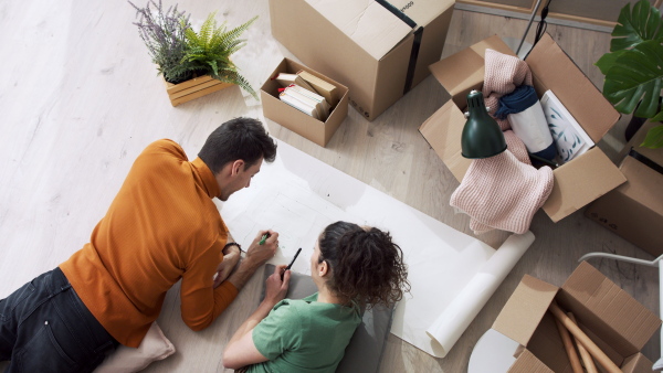 Top view of happy young couple owners in new flat, moving in and planning. New home and relocation concept.