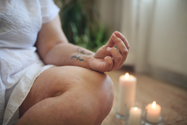 A close-up of overweight woman meditating at home.