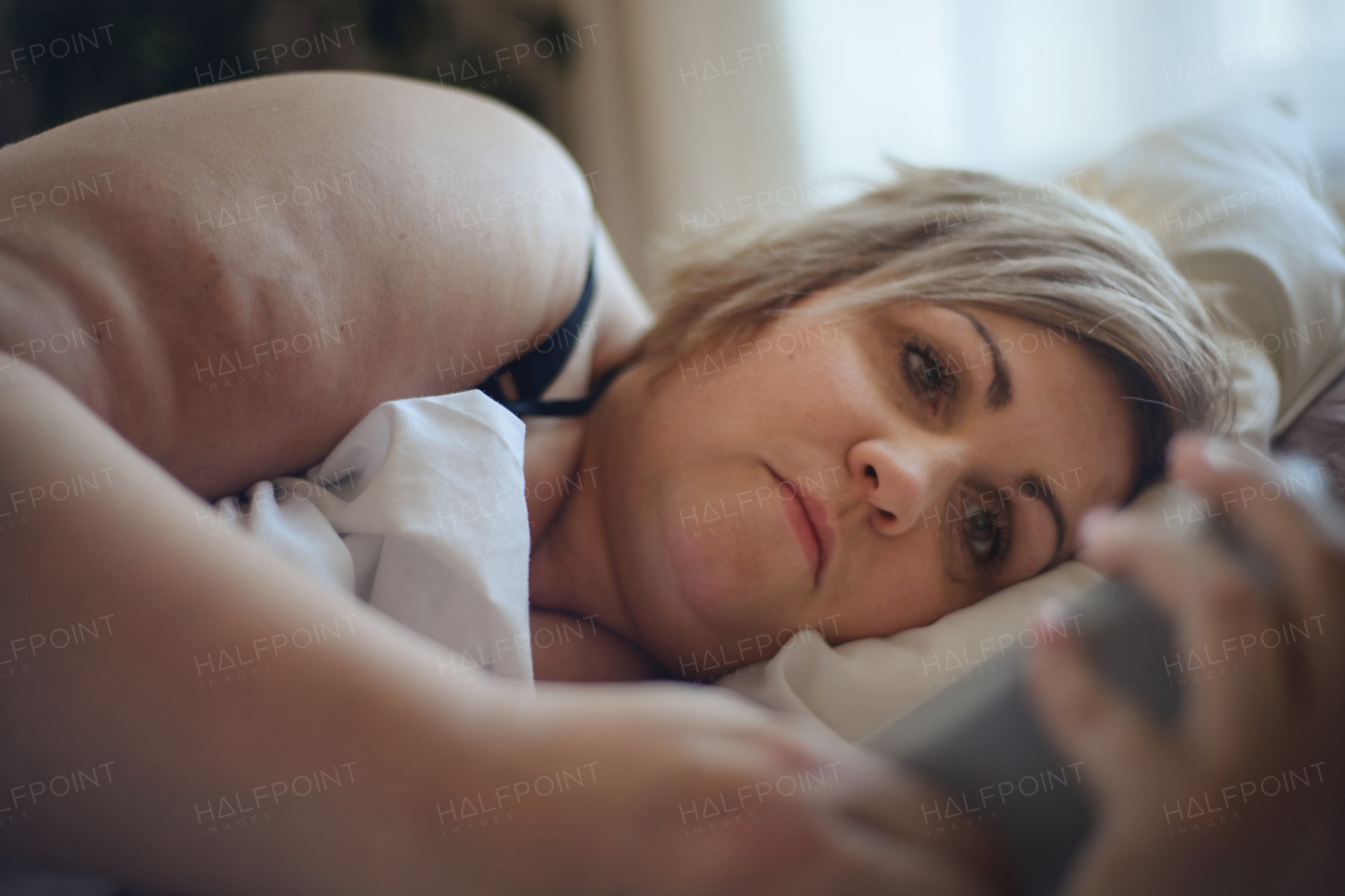 A depressed lonely fat woman lying in bed at home and thinking.