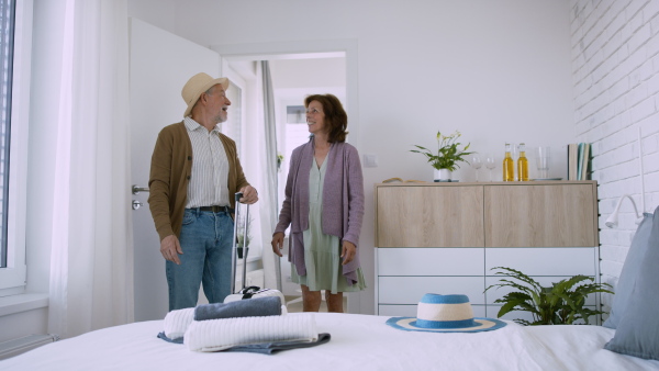 A senior couple arriving in hotel room, holiday a concept.