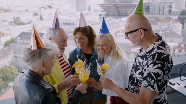 Front view of group of senior friends having party outdoors on balcony.